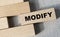 MODIFY - word on a wooden bar on a gray background