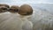 Moeraki boulders in the blurred Pacific Ocean waves