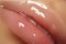 Moisturizing lip balm, lipstick. Close-up of a beautiful wet lips. Full lips with gloss makeup. Filler Injections