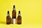 Moisturizing product in a dark glass bottles with pipette. Serum in glass bottles with a pipette on wooden cube on yellow backgrou