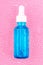 Moisturizing serum in glass bottle with white pipette on pink background with water drops. Hyaluronic acid for hydration