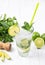 Mojito cocktail with fresh limes and mint leaves in a glass on a light wooden background