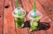 Mojito non-alcoholic, mint lemonade in plastic glasses on a wooden red background