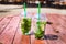 Mojito non-alcoholic, mint lemonade in plastic glasses on a wooden red background