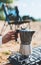 Moka pot coffee morning picnic lifestyle outdoor, person cooking hot drink in nature camping, cooker prepare breakfast campsite