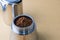 Mokapot coffee brewing with ground coffee beans isolated on brown background