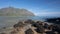 Mokolii Island [also known as Chinamans Hat] rocky beach looking toward Kualoa mountains on the North Shore of Oahu Hawaii USA