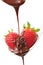 Molten chocolate being poured over two strawberries