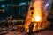 Molten iron pouring from blast furnace into ladle container, steel foundry factory, heavy metallurgy industry