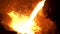 Molten steel being transferred from furnace to ladle in steel plant for further processing. Stock footage. Details of