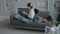 Mom and African daughter sit on sofa in modern living room back to back and read books. Motherhood and childhood