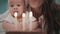 Mom with baby blowing birthday candle. Woman with kid blowing candles on cake