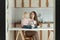Mom and baby in kitchen. Young mom and toddler have breakfast at home