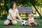 Mom and baby roll soccer ball to each other sitting at football field. Mother and son playing together. Summer family fun outdoors