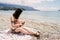 Mom breastfeeds little girl while holding her on her knees on the pebble beach