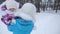 Mom carries in her arms a small happy daughter walking along a snowy road. Baby and mother on a winter walk. Child