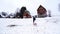 Mom carries a small child on a sled up the hill to the wooden houses