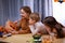 Mom carves Jack lantern out of a pumpkin, and daughter and son are watching closely. The family is sitting at a table in