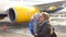 Mom and child are standing near plane at airport.