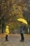 Mom and child are standing in rain in autumn park. Walking in rainy weather. Vertical frame