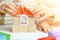 Mom and child together build a house of cubes and blocks constructor. Close up of hands holding roof. Playing parents and children