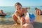 Mom with children at sea wipes the child`s face from sea sand on the beach