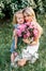 Mom with cute little daughter with flowers outside at the sunset. Concept of happy motherhood