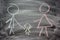 Mom, dad and child drawn in chalk on black slate as symbol of family love