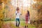 Mom, dad and daughter walk through the autumn forest. Daughter sits on father`s shoulders