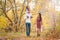 Mom, dad and daughter walk through the autumn forest. Daughter sits on father`s shoulders