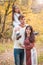 Mom, dad and daughter walk through the autumn forest. Daughter sits on father`s shoulders