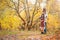 Mom, dad and daughter walk through the autumn forest. Daughter sits on father`s shoulders