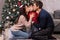 Mom and dad kiss a young son near the Christmas tree. Happy New Year`s morning with the family. Parents and child