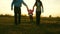 Mom and dad play with baby. parents raise baby`s hands in rays of sunset. concept of family happiness. happy kid jumping