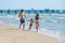 Mom, dad and son walk along the sand beach. Waves and pier in background.