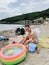 Mom and daughter on the beach. Play in the sand with a bucket, near a small inflatable pool.