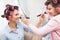 Mom and daughter in a beauty salon. They have curlers in their hair. Mother and daughter make makeup to each other.