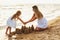 Mom and daughter build sand castles on the beach on a sunny summer day. Family holidays by the sea