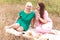 Mom and daughter celebrate mother`s day on a summer picnic. Beautiful adult and young women relax in nature with food and drink