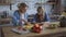 Mom and daughter cook together in a large bright kitchen. Mom cuts juicy peppers, a girl reads a recipe on a tablet 4K