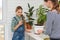 Mom and daughter cut indoor plants for propagation by cuttings, the girl happily holds the cutting in her hands and looks into the