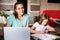 Mom and daughter do school lessons together. Mom looks at the camera and smiles