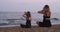 Mom and daughter do yoga and meditate together on beach in evening