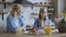 Mom and daughter laugh in the kitchen, drink orange juice with cookies and muffins. cute happy family talk 4K