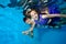 Mom and daughter are laughing, swimming and playing underwater in the pool in beautiful dresses on blue background.