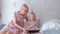Mom and daughter look in tablet. Young attractive blond woman with her little charming daughter in pink dresses watching