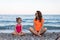 Mom and daughter meditate on the beach, free space