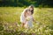 Mom and daughter on a picnic in the chamomile field. Two beautiful blondes in chamomile field on a background of horse