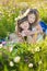 Mom and daughter on a picnic in the chamomile field. Two beautiful blondes in chamomile field on a background of horse