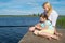 Mom and daughter on the pier, against the backdrop of a beautiful landscape, hold a fishing pole to catch fish, close-up, there is